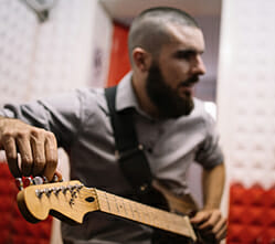 Image of a man tuning a guitar in a soundproof studio