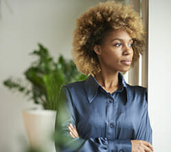 Image of a woman leaning by a window, contemplating coping skills for addiction