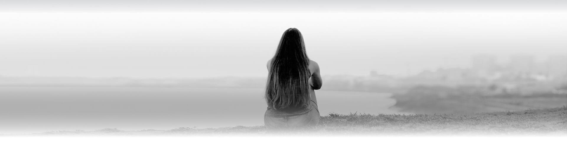 Image of a woman sitting alone outside, thinking about getting help for her substance use