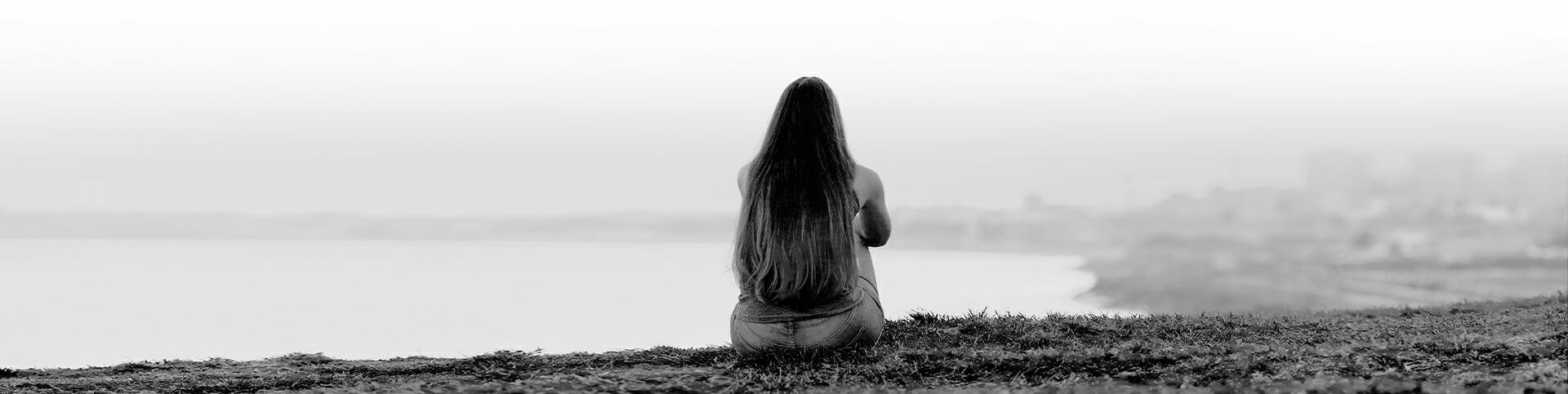 Image of a woman sitting alone outside, thinking about getting help for her substance use