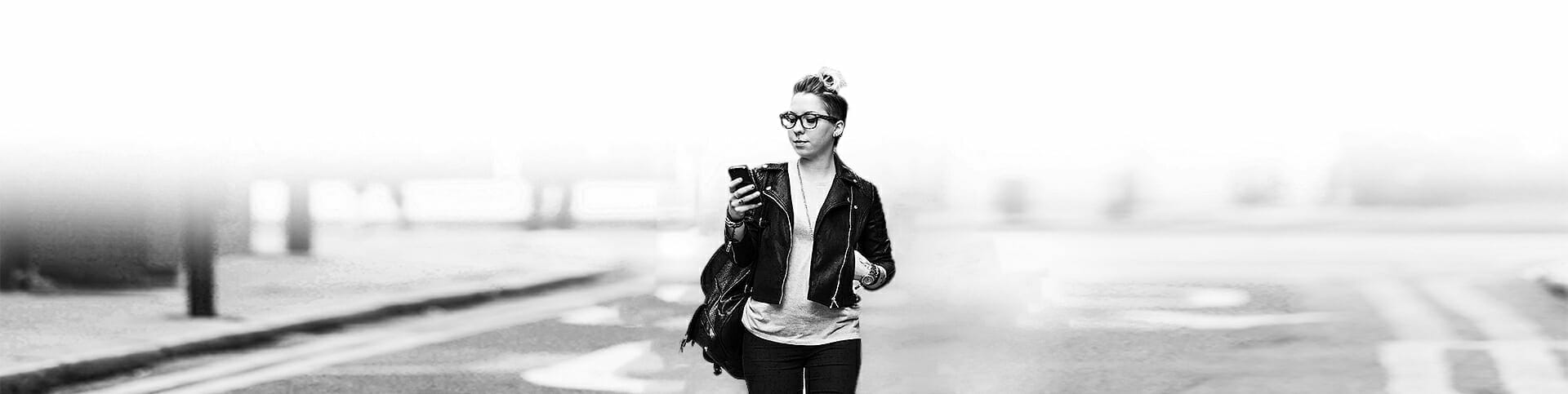 Image of a woman walking while using her cell phone looking for options to treat her substance use disorder
