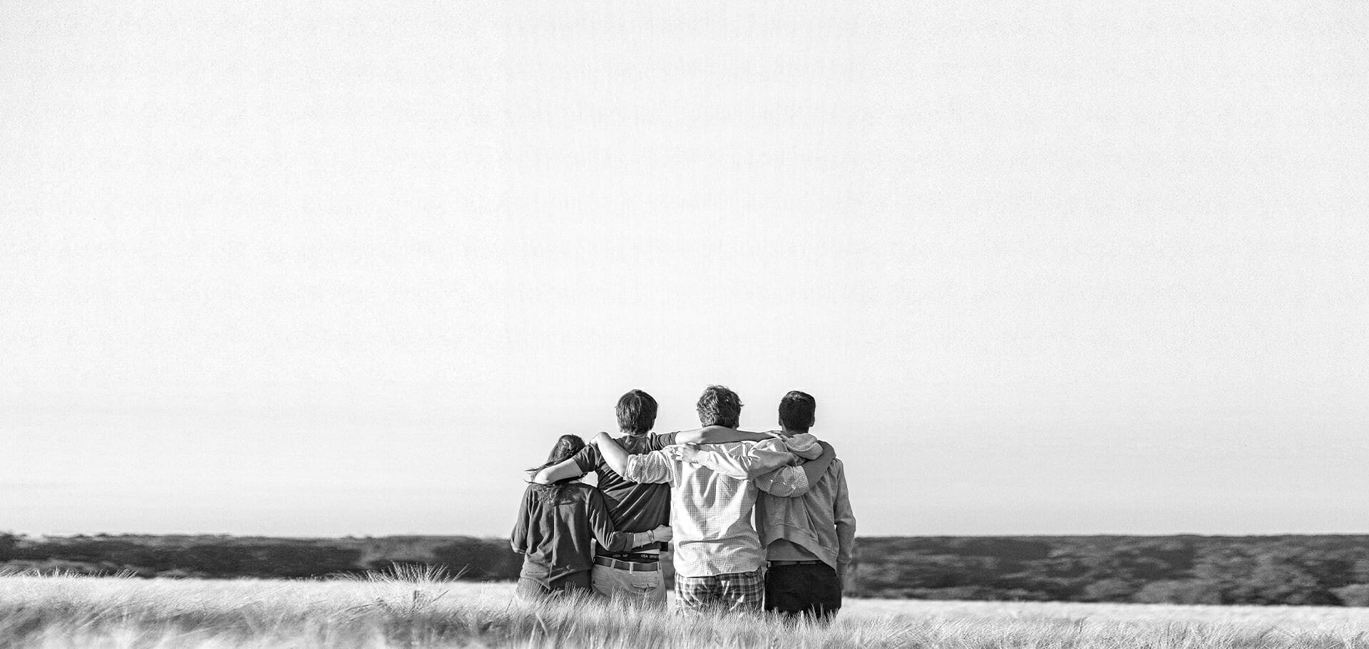 A group of 4 individuals outside locking arms, representing a start to a new life with the help of substance use disorder treatment